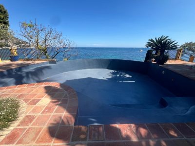 Piscine à débordement face à la mer, revêtement Aquabright bleu nuit