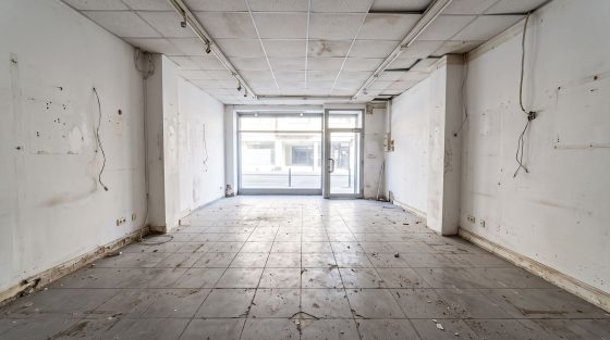 Local commercial vide au carrelage gris usé et ébréché